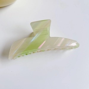 Détail d'une pince à cheveux en acétate vert clair avec courbe fluide et dents antidérapantes