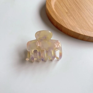 Dettaglio ravvicinato di una pinza per capelli in acetato con effetto marmo colorato