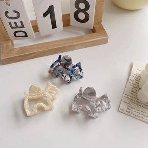 Three minimalist dog-shaped acetate hair claws with elegant marble textures in diverse colors
