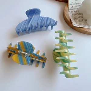 Three-piece set of acetate claw clips with marble textures on a minimalist background