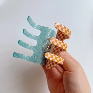 Detail of checkered acetate hair claw clip with glitter finish and metal spring hinge