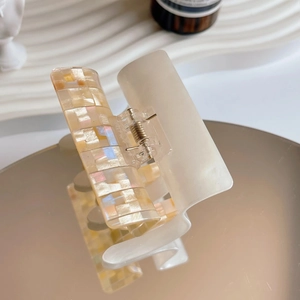 Macro detail of checkered acetate hair claw clip with pearlescent finish and spring