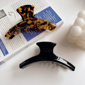 Elegant tortoiseshell and glossy black large hair claws on aesthetic book background