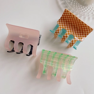 Three acetate hair claws featuring pink, orange checkerboard, and green plaid patterns