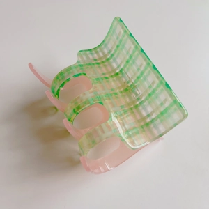 Detail of pink and green checkered cellulose acetate hair claw clip with glossy finish