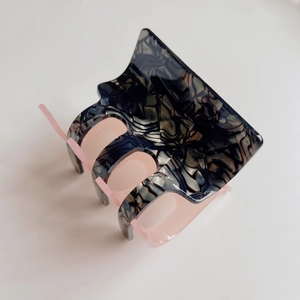 Macro detail of checkered acetate hair claw with marble texture and pink inner lining