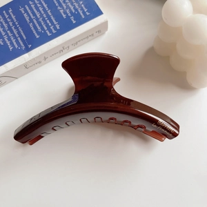 Close-up of a dark brown glossy acetate hair claw clip with golden lettering detail