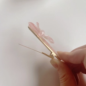 Détail d'une pince à cheveux nœud en acétate rose avec base en métal doré