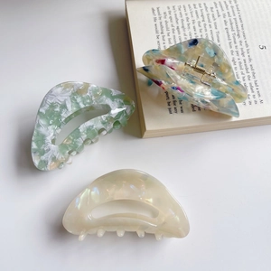 Three elegant vintage acetate hair claws in marble and cream patterns on a clean background