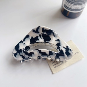 Close-up of marble pattern hair claw clip with glossy finish and metal hinge detail