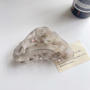 Close-up of pearl marble acetate hair claw with elegant hollow design on white background