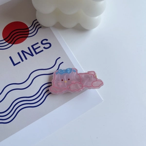 Close-up of a pink cartoon resin hair clip with a blue bow on a white decorative card