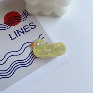 Close-up of a yellow duck hair clip made of acrylic with delicate pearl texture detail