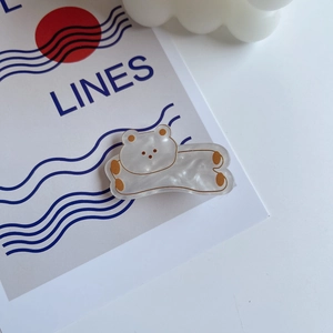 Detail of a pearlescent acrylic bear hair clip on an artistic minimalist background card