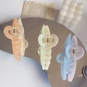 Détail de trois pinces à cheveux bicolores en acétate crème sur un miroir élégant
