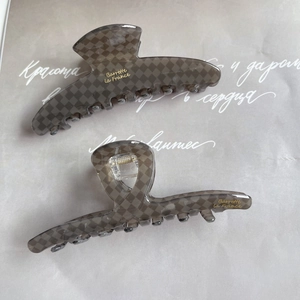 Detail of grey checkered acetate hair claws with gold springs and French lettering