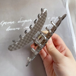 Detailed view of large grey checkered acetate hair claw clip held in hand with metal spring