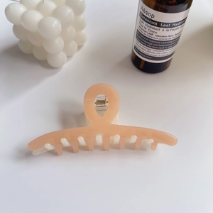 Gros plan sur la pince à cheveux en acétate pêche avec ressort doré brillant