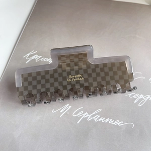 Detail view of acetate checkered hair claw clip with golden Barrette la France logo