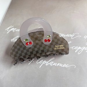 Macro detail of acetate checkerboard shark clip with crystal cherry and golden logo