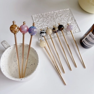 Detail of assorted tortoiseshell acetate hair pins with golden metal sticks in a vase