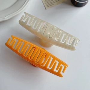 Detail of large acetate hair claws in orange and pearl white with smooth edges