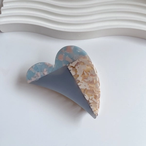 Detail view of heart-shaped acetate hair claw with tricolor patchwork textures