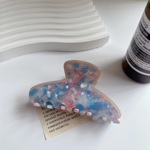 Dettaglio di un fermaglio per capelli in acetato marmorizzato blu e rosa con finitura lucida