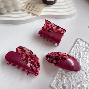Close-up of three acetate floral claw clips with Barrette la France golden lettering