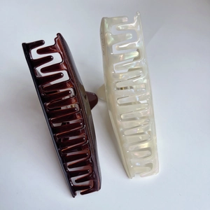 Détail macro de grandes pinces à cheveux en acétate blanc perlé et ambre effet écaille