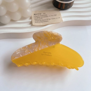 Nahaufnahme einer Haarspange aus Harz in Gelb und Creme-Marmor auf einem Dekotablett