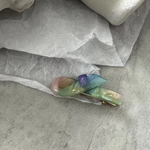 Vue détaillée d'une barrette à cheveux en résine dégradée colorée avec ornement violet
