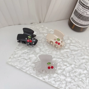 Nahaufnahme von drei Acetat-Haarklammern mit Kirschmustern aus Strass in verschiedenen Farben