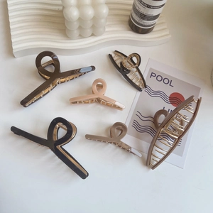 Flat lay of minimalist resin hair claws in neutral colors with golden metal teeth