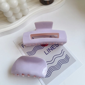 Close-up of lilac acetate hair claws with a cutout design on a stylish ceramic plate