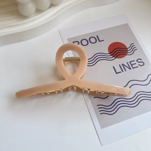 Detail view of peach translucent acrylic hair claw clip with a strong gold metal spring