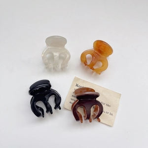 Set of four glossy acetate hair claws in cream amber black and brown on a grey background