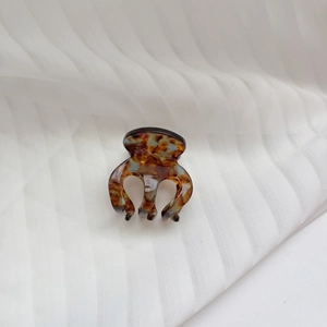 Macro shot of small acetate claw clip with amber tortoise shell pattern on fabric