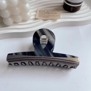 Close-up of dual-tone grey marbled acetate hair claw clip with gold brand lettering