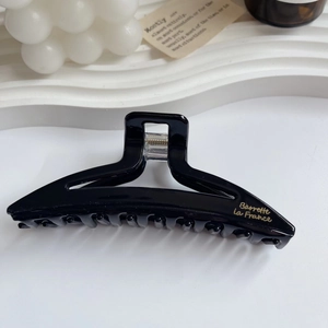 Detail of a large black acetate hair claw clip featuring elegant gold Barrette La France text