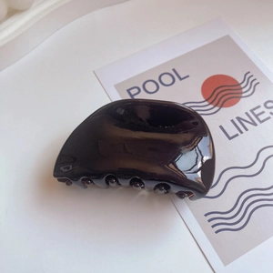 Macro detail of the polished black acetate hair claw clip with its strong teeth design
