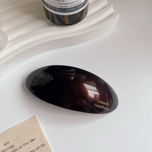 Detail view of handmade dark brown acetate spring hair clip with gold lettering
