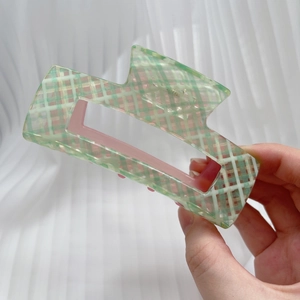 Close-up of a large green and white checkered hair claw clip with pink inner details