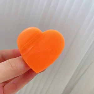 Vue détaillée de la pince à cheveux orange en forme de cœur avec une finition résine