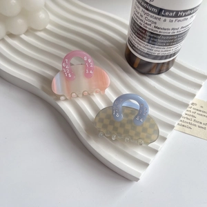 Detailed macro view of two cellulose acetate hair claws in pink gradient and checkered patterns