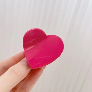 Vue détaillée d'une pince à cheveux rose en forme de cœur avec finition brillante