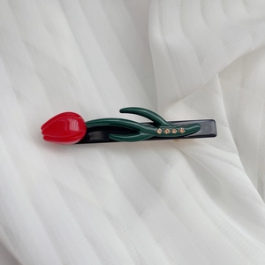 Détail de la pince à cheveux tulipe rouge avec feuilles vertes et strass jaunes