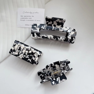 Detailed view of three black and white marble acetate hair claws in various sizes