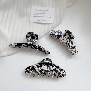 Three acetate hair claws with black and white marble patterns on white background