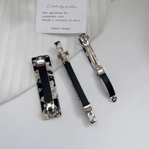 Detailed view of three marble pattern acetate hair clips with silver metal spring mechanism